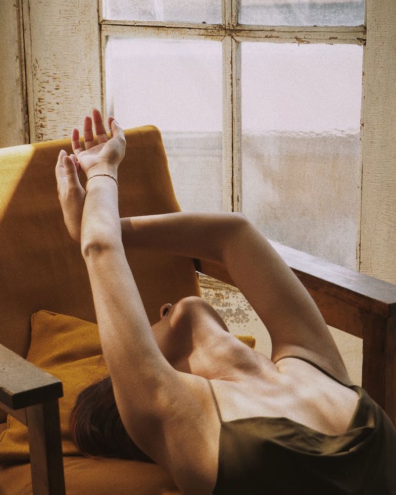 Woman in a peaceful stretching pose bathed in a soft peach light.